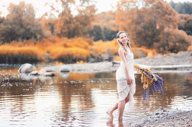 Beautiful girl with a bouquet of blue flowers on nature in autumn