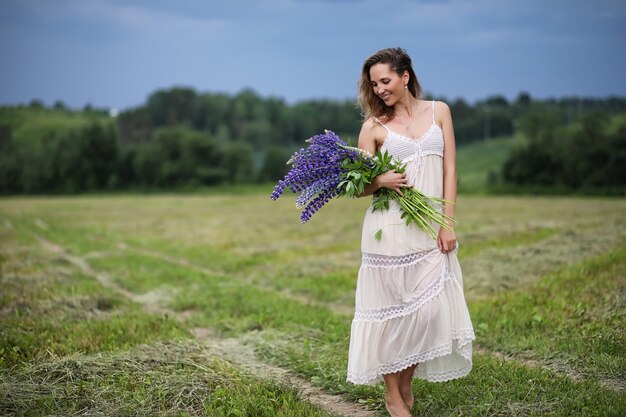 Bella ragazza con un mazzo di fiori blu sulla natura in estate