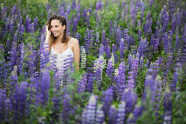 Beautiful girl with a bouquet of blue flowers on nature in summer