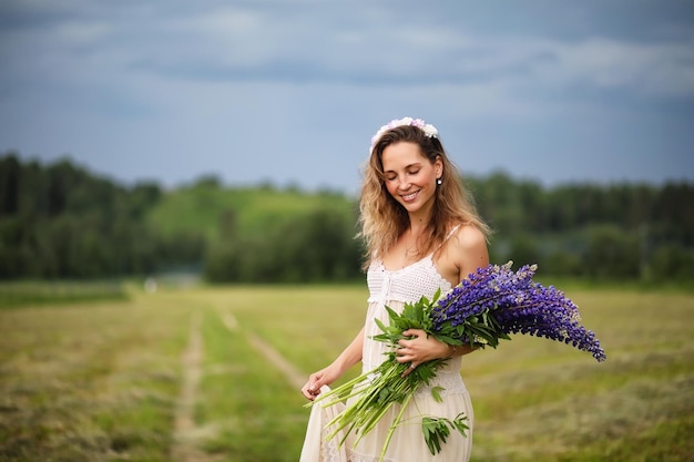 Beautiful girl with a bouquet of blue flowers on nature in summer