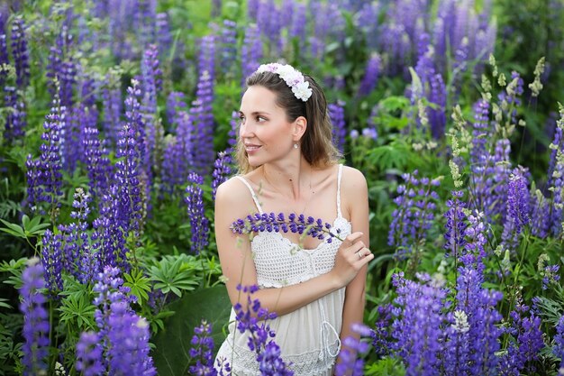 Foto bella ragazza con un mazzo di fiori blu sulla natura in estate