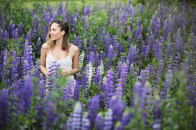 Beautiful girl with a bouquet of blue flowers on nature in summer