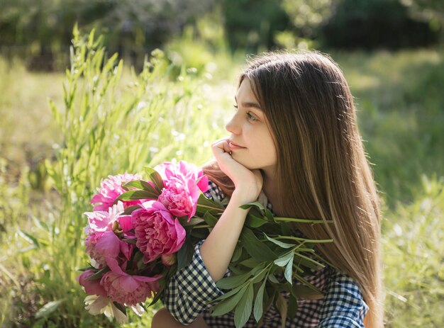 Beautiful girl with a bouquet of peonies