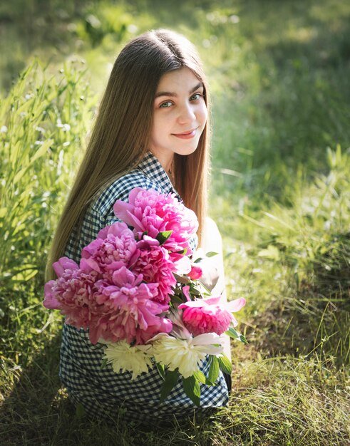 Beautiful girl with a bouquet of peonies