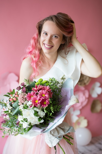 Beautiful girl with a bouquet on a pink background