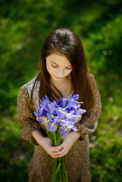 Bella ragazza con un mazzo di iris viola viola nelle sue mani