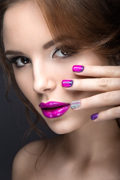 Beautiful girl with a bright evening make-up and purple manicure with rhinestones. Nail design. Beauty face. Picture taken in the studio on a black background.