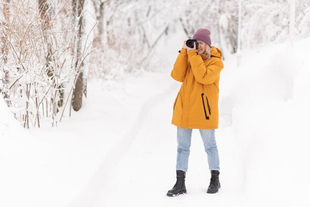 カメラを手にした美少女が雪の公園で冬の写真を撮る