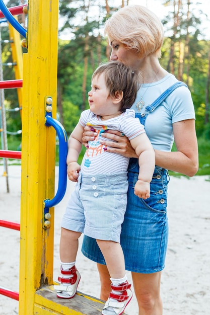 子供の遊び場で子供を持つ美しい少女