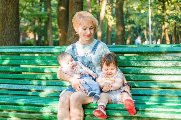 公園のベンチに座っている子供を持つ美しい少女