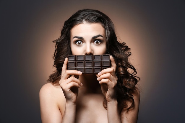 Beautiful girl with chocolate on dark background