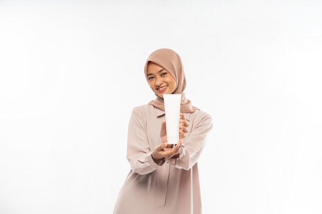 Beautiful girl with clean skin holds a white template tube