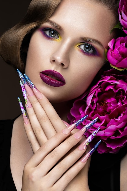 Bella ragazza con trucco colorato fiori acconciatura retrò e unghie lunghe manicure design la bellezza del viso