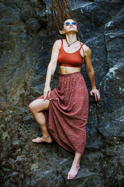 Beautiful girl with dreadlocks dressed hippie styleposes outdoors