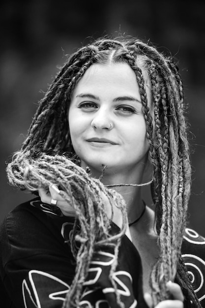 Beautiful girl with dreadlocks dressed hippie styleposes outdoors