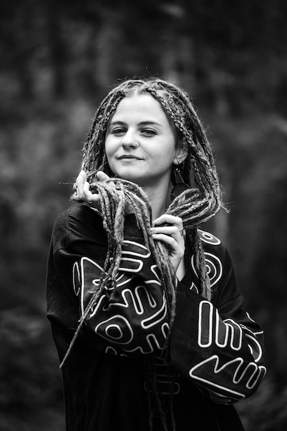 Beautiful girl with dreadlocks dressed hippie styleposes outdoors