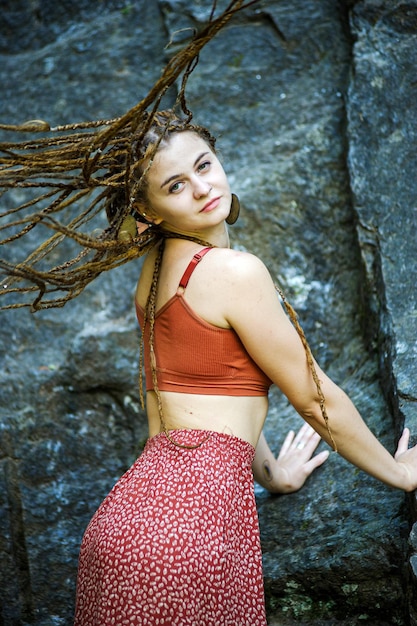 Beautiful girl with dreadlocks dressed hippie styleposes outdoors