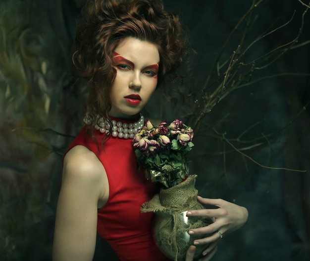 Beautiful girl with dry roses in gothic decoration