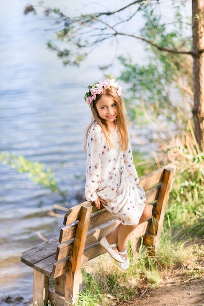 Beautiful girl with floral wreath on a bench