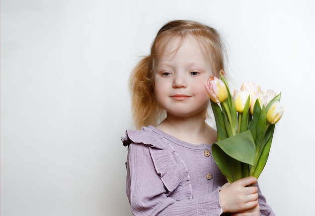 写真 白い背景に花を持つ美しい少女