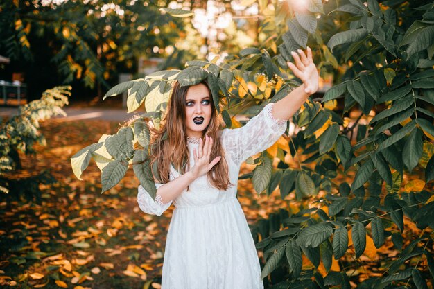 Beautiful girl with gothic make up and funny face expression posing in summer park.