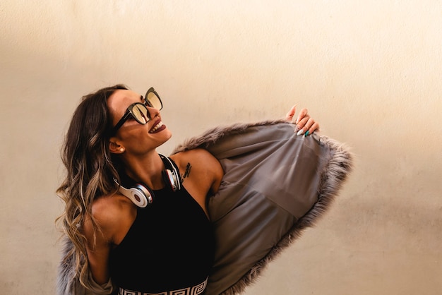 Фото Красивая девушка в наушниках слушает музыку и танцует на открытом воздухе. белый фон стены