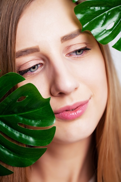 Beautiful girl with healthy skin and green plant