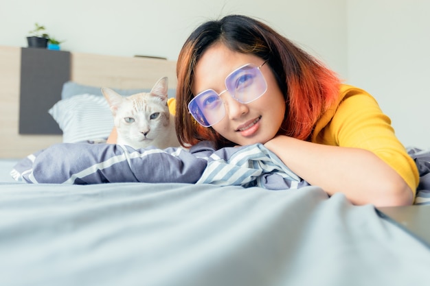 Beautiful girl with her cat on the bed in the bedroom