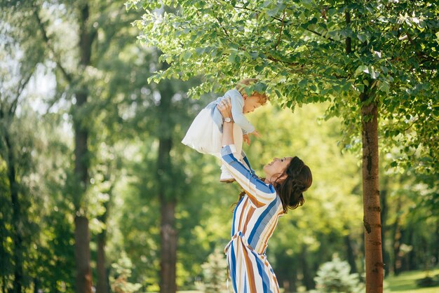 公園で彼女の腕に小さな娘を持つ美しい少女
