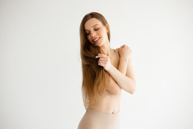 Фото Красивая девушка с длинными волосами в компрессионной одежде телесного цвета