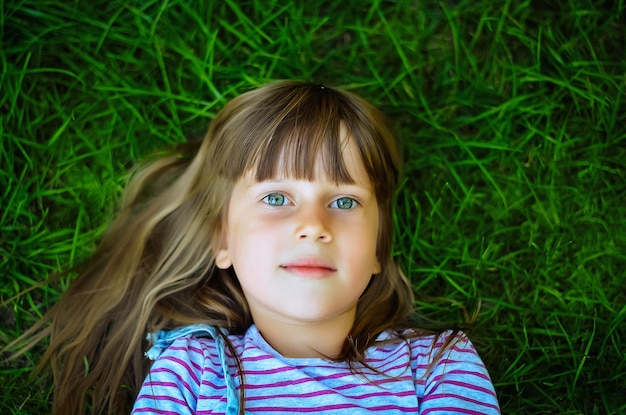 A beautiful girl with long hair nine years old lies on the grass vacation vacation in the park