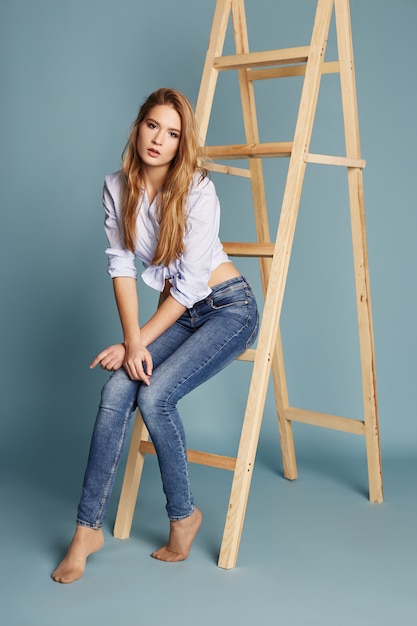 Beautiful girl with long hair sitting on ladder