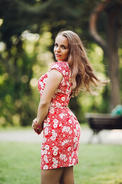 Beautiful girl with long wavy hair and make up, standing back to camera and looking, posing over shoulder