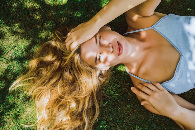 길고 흰 머리를 가진 아름 다운 소녀는 푸른 잔디와 미소에 놓여 있습니다. 곁눈질. 눈이 가늘고 교활한 미소.