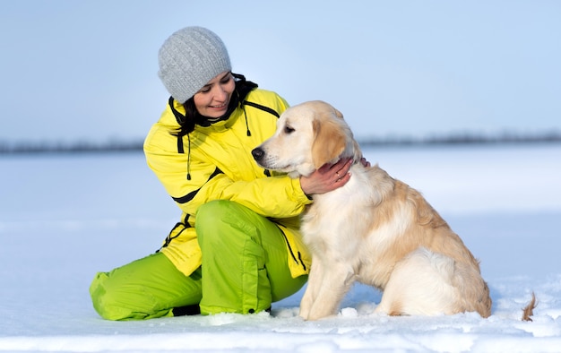 冬の外で素敵な若いレトリーバー犬と美しい少女