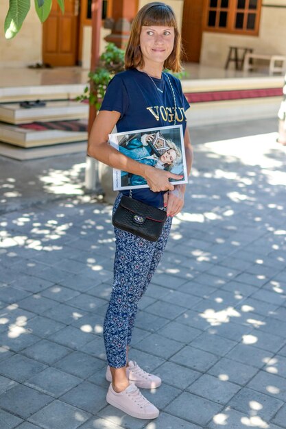 Foto una bella ragazza con una rivista in mano e una borsa fatta di pelle di pitone si trova per strada