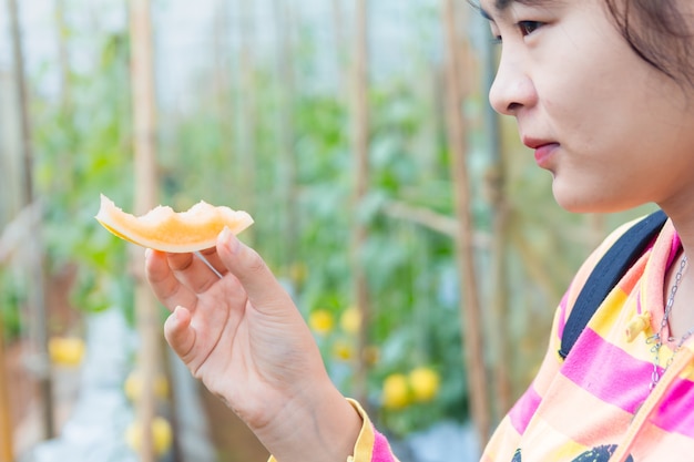 Beautiful girl with melons in his hands. Young woman eating melon at garden.