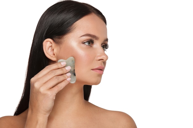 Beautiful girl with natural makeup and clean skin Holds in hand a jade face scrubber