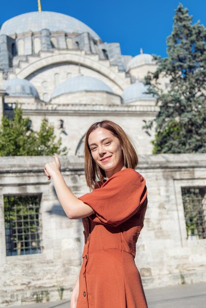 Beautiful girl with orange colored dress posing in front of the Suleymaniye Mosque