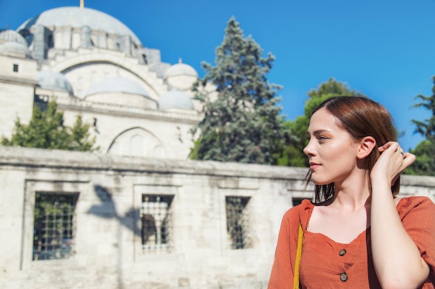 Beautiful girl with orange colored dress posing in front of the Suleymaniye Mosque