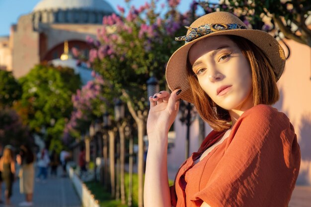 Beautiful girl with orange colored dress posing with Hagia Sophia during sunset from Istanbul