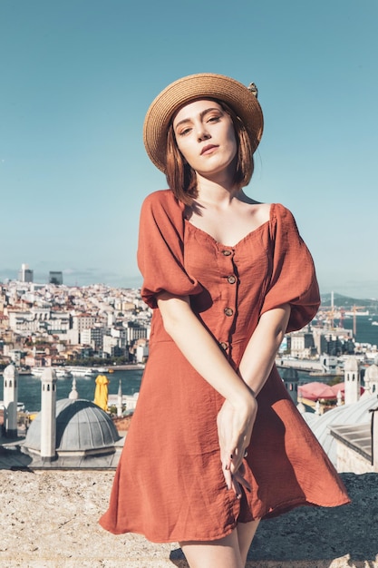 Bella ragazza con il vestito di colore arancione che posa con la scena di costantinopoli