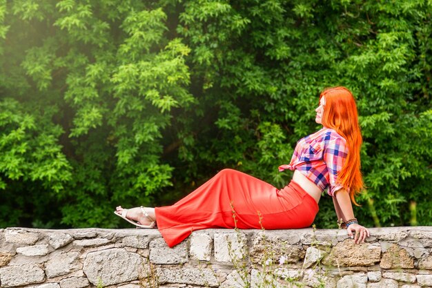 Beautiful girl with orange hair in plaid shirt and red pink skirt