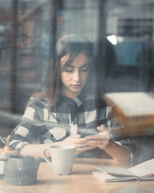 Beautiful girl with a phone in a cafe