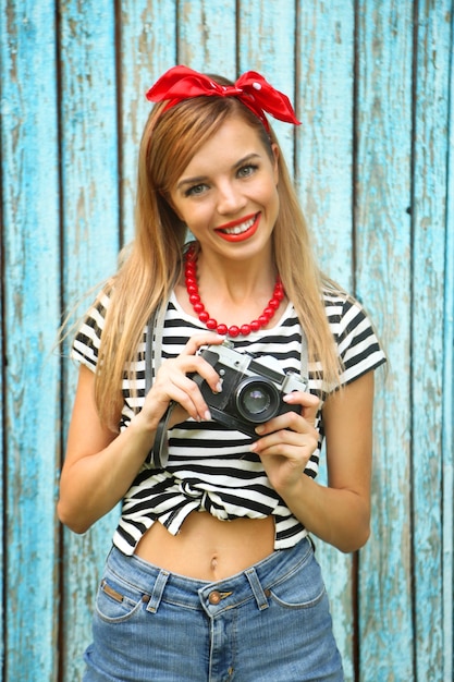 Foto bella ragazza con bel sorriso e macchina fotografica su fondo di legno di colore