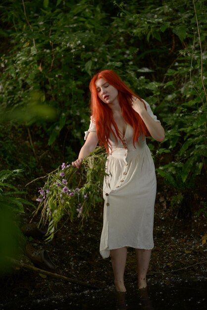 Photo beautiful girl with red hair on the bank of the pond