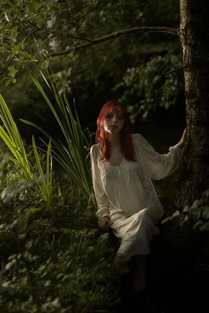 Foto bella ragazza con i capelli rossi sulla riva dello stagno