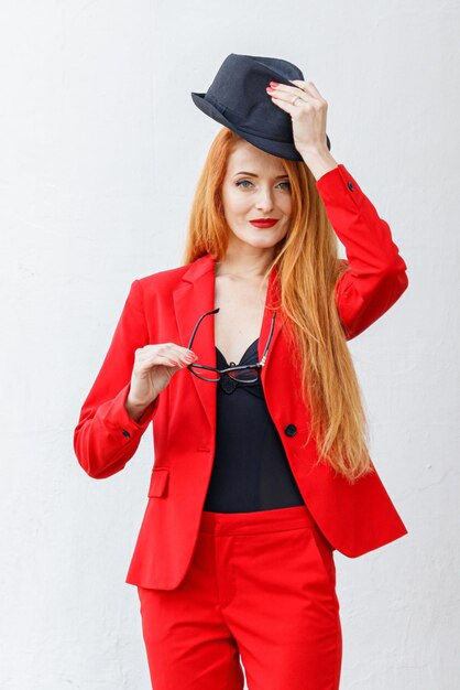 Beautiful girl with red hair dressed in a red business suit Business portrait