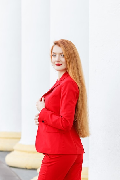 Bella ragazza con i capelli rossi vestita con un tailleur rosso ritratto di affari