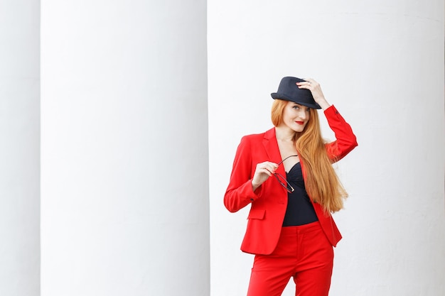 Beautiful girl with red hair dressed in a red business suit Business portrait